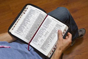 A man holds an open Bible and reads